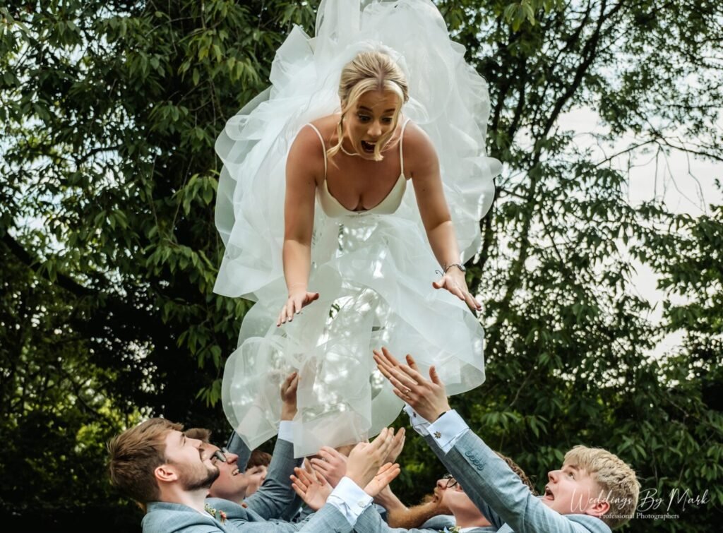Fun wedding group photo of the bride being thrown into the air by guests at Mosborough Hall Hotel, Sheffield