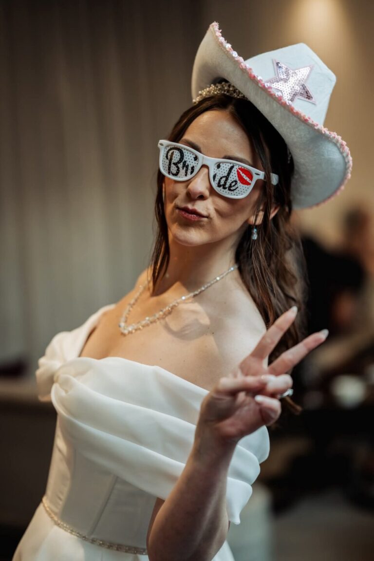 Bride wearing fun party cowboy hat and sunglasses during the evening reception at Stirk House.