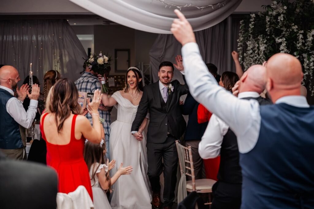 Bride and groom making a grand entrance into the Stirk House wedding breakfast cheered by guests.