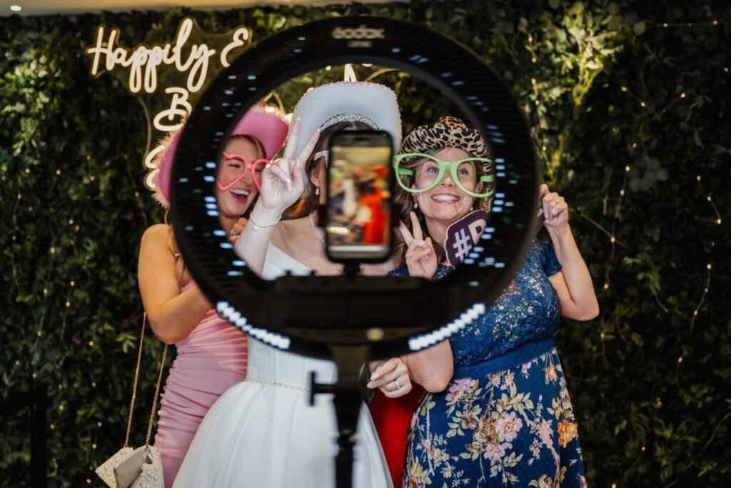 Wedding guests having fun with props at the selfie booth station during Stirk House evening party.