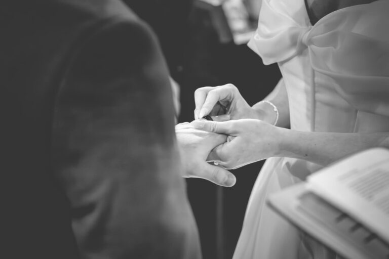Close up black and white photo of wedding ring exchange during church ceremony near Gisburn