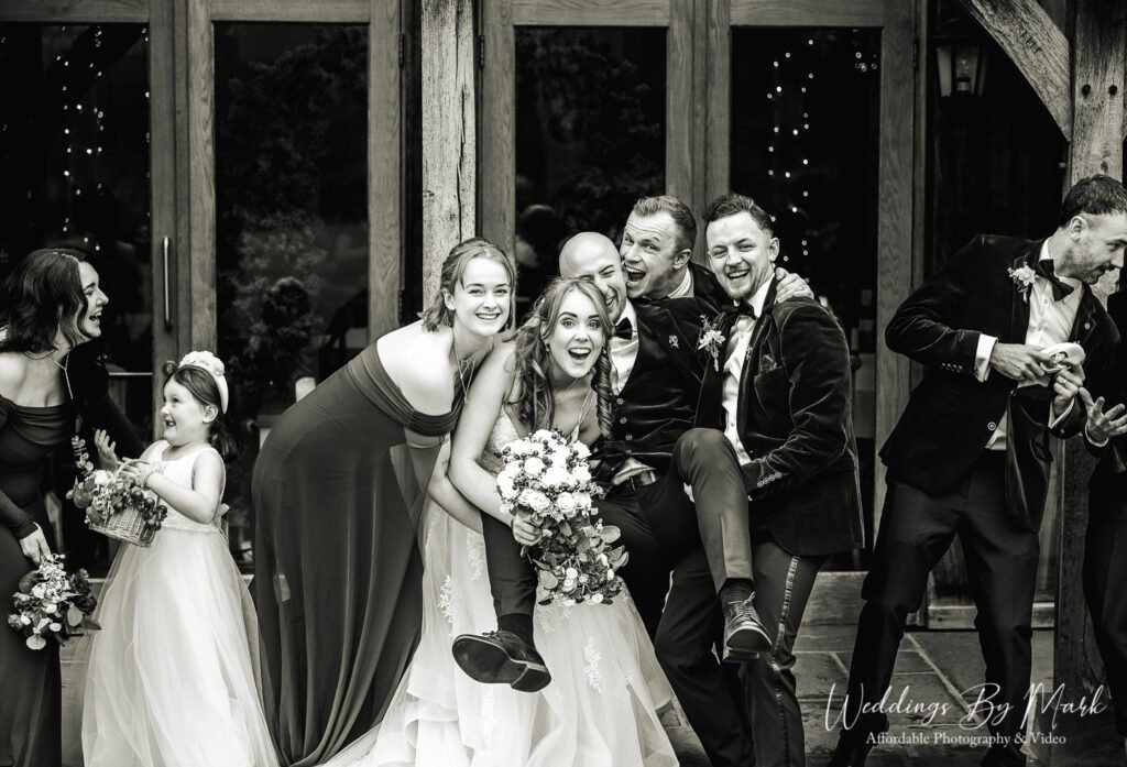 Fun and relaxed wedding photography showing the bridal party laughing and joking together outside The Oak Tree of Peover