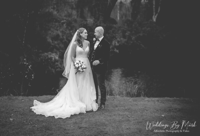 Romantic black and white wedding portrait of Katie and Mathew standing by the lake at The Oak Tree of Peover