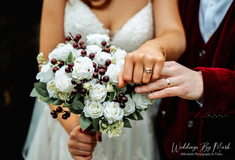 Detail shot of the newlyweds' wedding rings and white rose bouquet captured by a wedding photographer at The Oak Tree of Peover