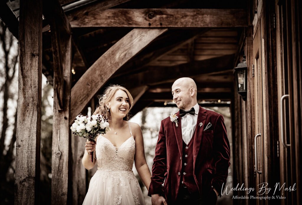 Natural candid moment of Katie and Mathew walking together under the rustic timber beams at The Oak Tree of Peover