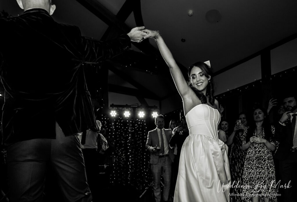 A timeless black and white capture of the first dance, featuring the groom spinning the bride, showing off the movement of her dress