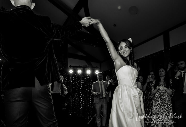 A timeless black and white capture of the first dance, featuring the groom spinning the bride, showing off the movement of her dress