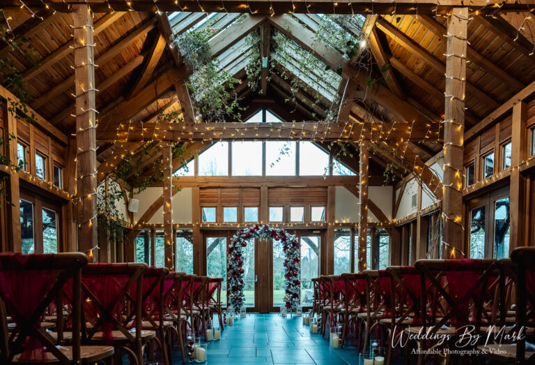 Stunning rustic ceremony barn setup with fairy lights and red sashes at The Oak Tree of Peover