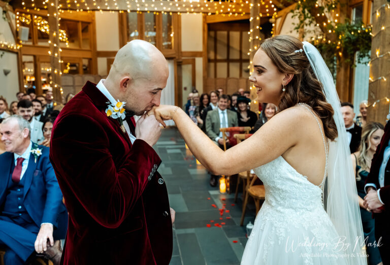 Emotional ceremony moment where Mathew kisses Katie's hand at The Oak Tree of Peover, captured in a documentary style