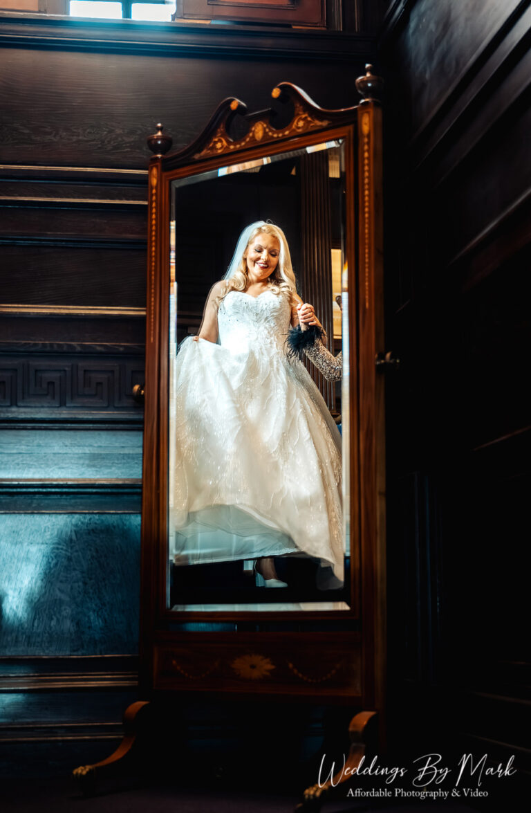 Wedding photography on the Eaves Hall staircase featuring a reflection in the gold mirror.