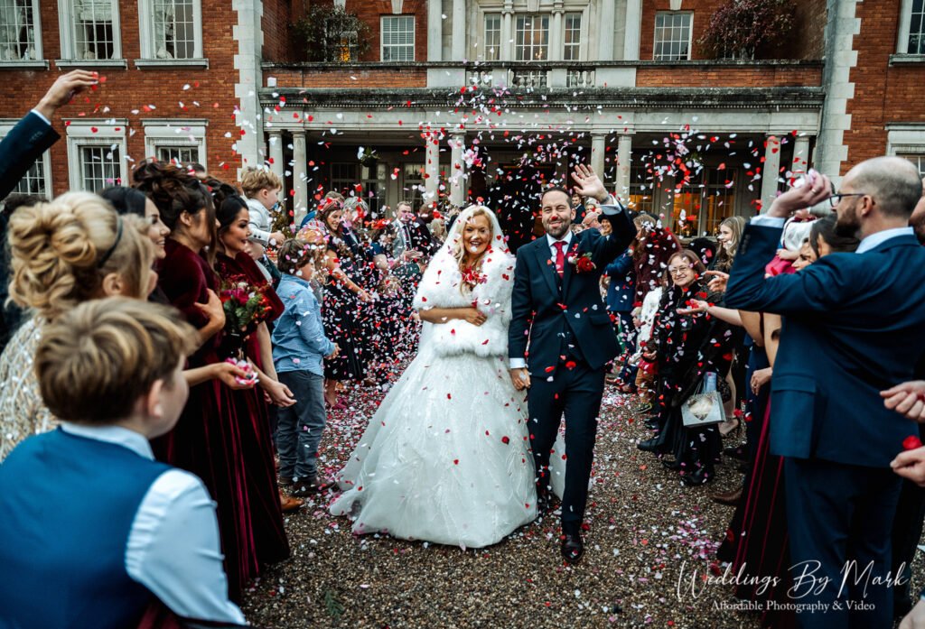 Maria and Jonny walking through confetti at their Eaves Hall wedding in the Ribble Valley.