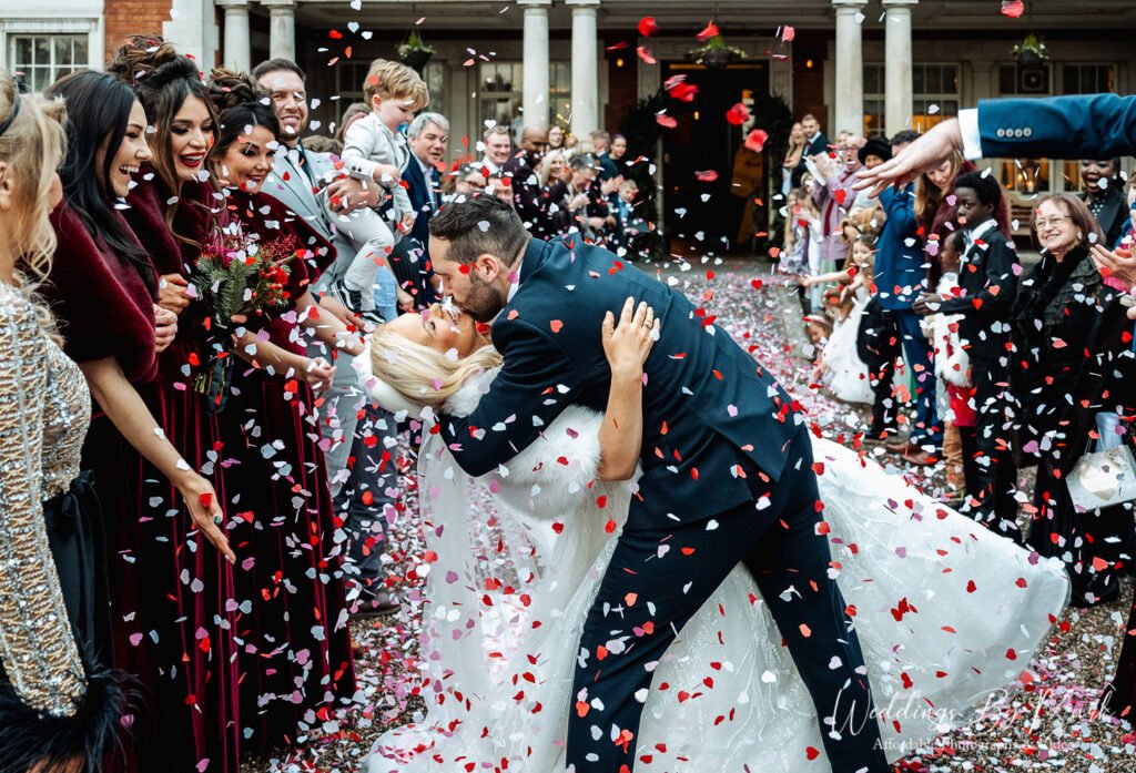 Joyful confetti throw on the front steps of Eaves Hall during a winter wedding.
