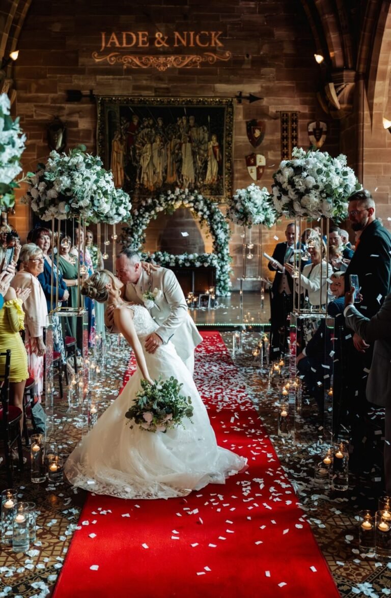 Romantic dip kiss for the bride and groom on the red carpet aisle of the Great Hall at Peckforton Castle, captured by a Cheshire wedding photographer.