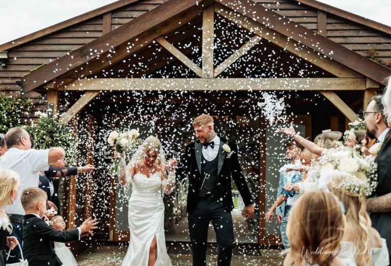 Laura and Nick walking through confetti outside Merrydale Manor