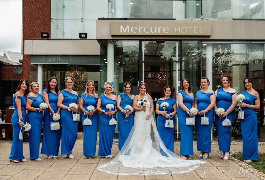Bride with bridesmaids in blue dresses outside Mercure St Helens hotel