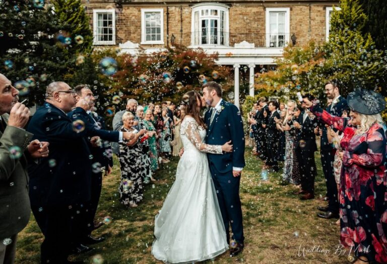 Claire and Richard kissing amid bubbles outside Ringwood Hall Hotel and Spa
